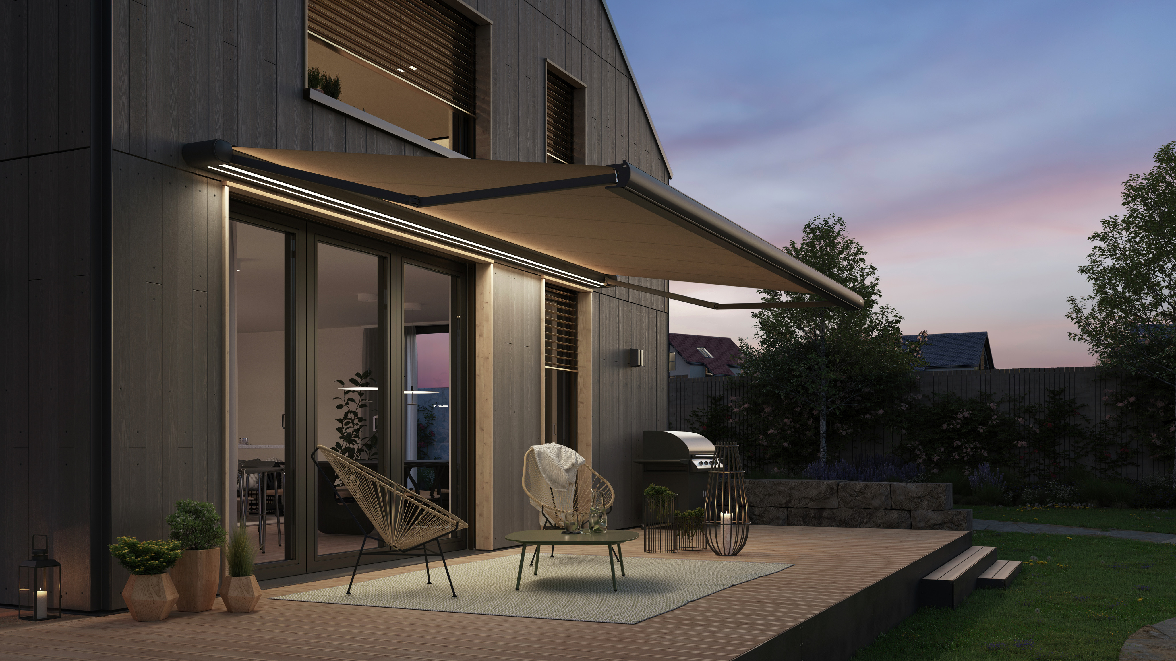 WAREMA Terrea K55 Gelenkarmmarkise mit eingeschalteter LED-Beleuchtung über einer Terrasse in der Abenddämmerung